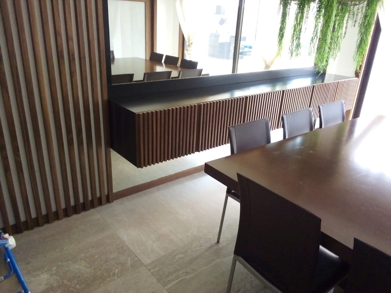 Sala de jantar com painel ripado e aparador suspenso